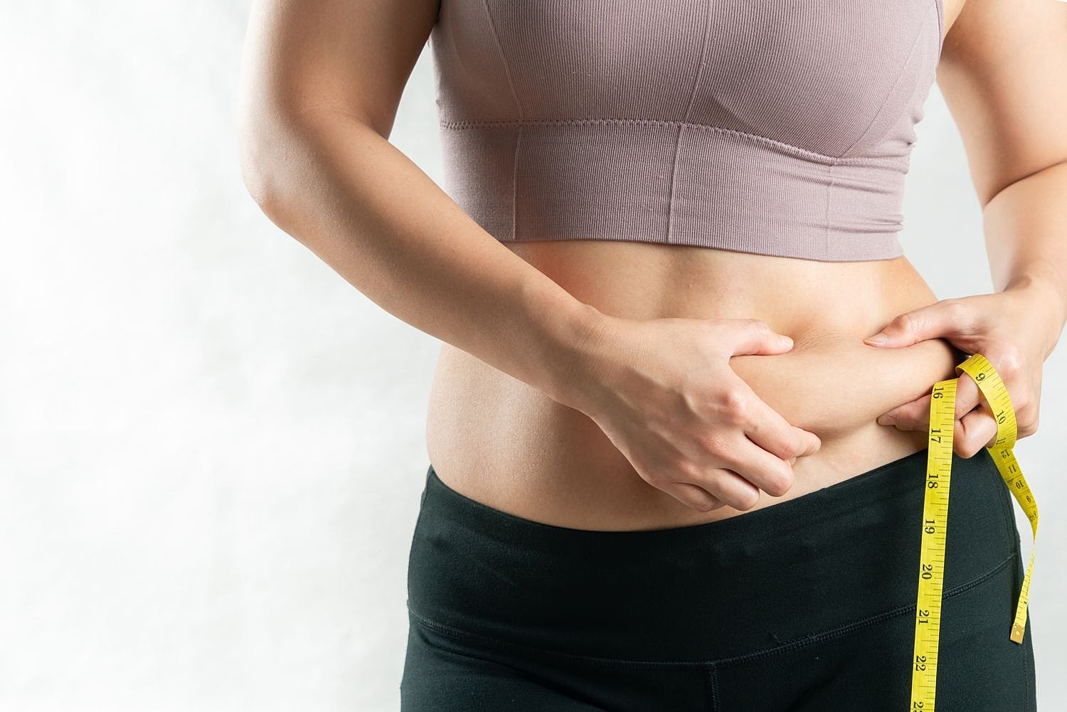Measuring waist with tape measure on stomach.