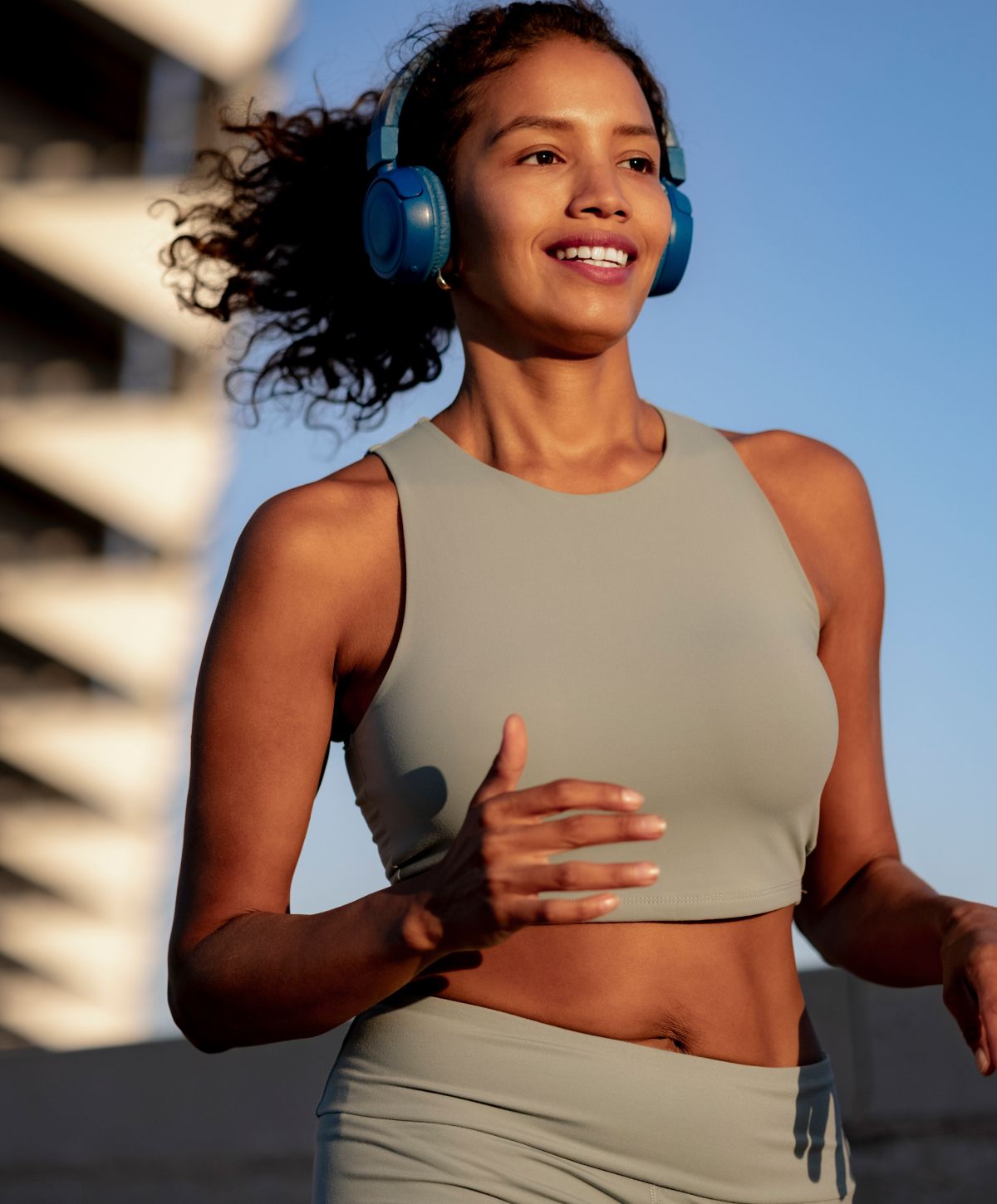 Woman jogging outdoors with headphones on.