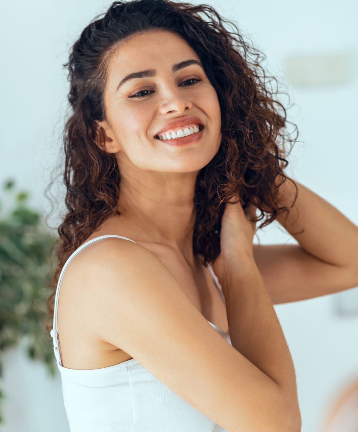 Smiling woman with curly hair in white top.
