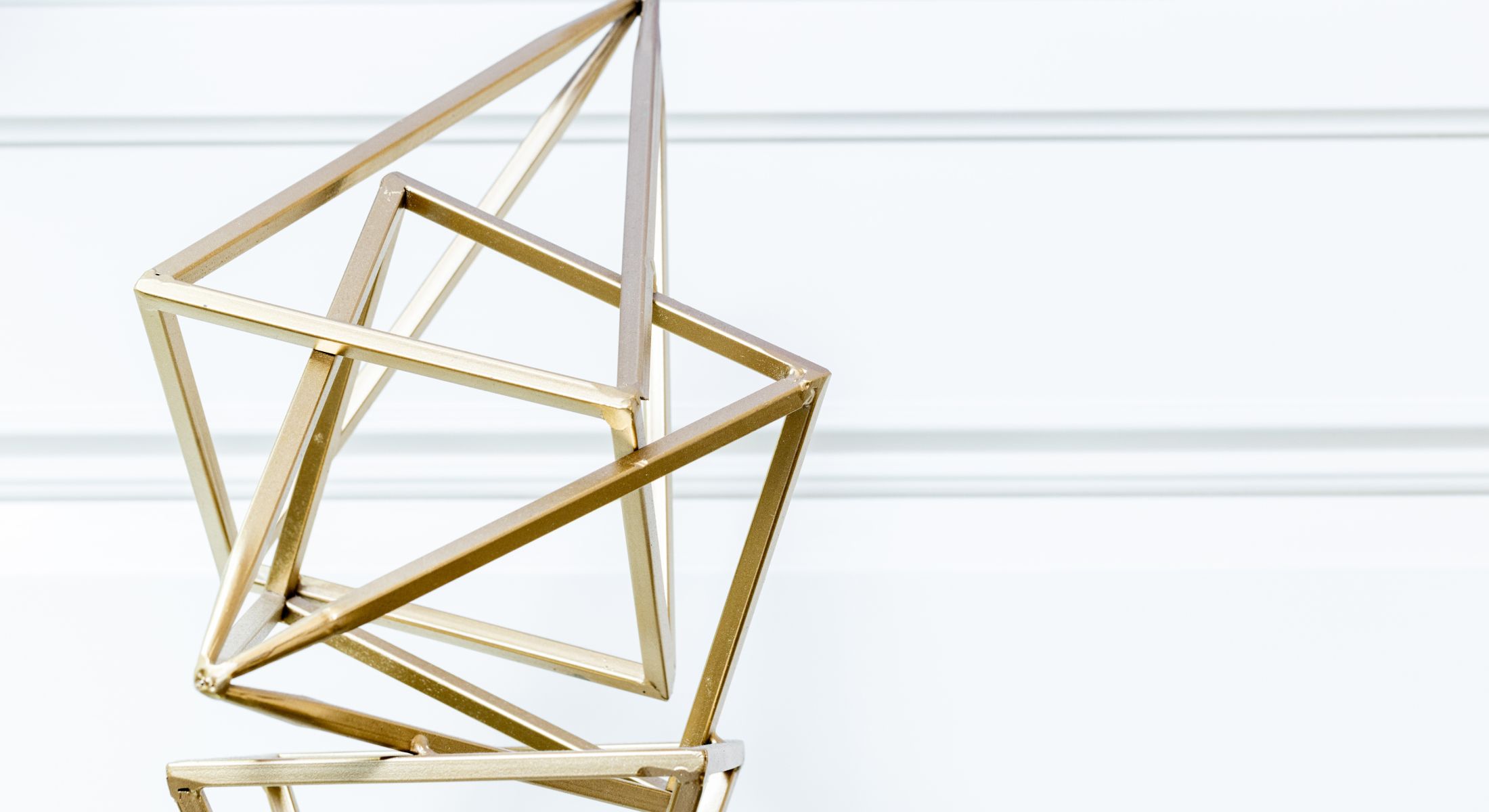 Geometric gold sculpture against white background.