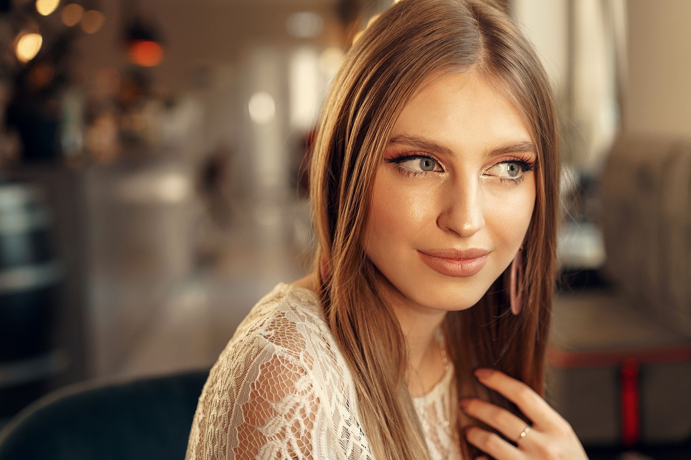 Young woman with long hair and lace top.