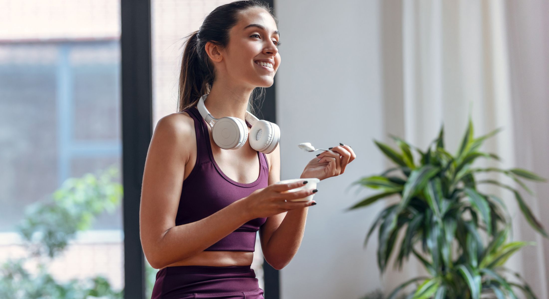 Woman enjoying yogurt with headphones on.