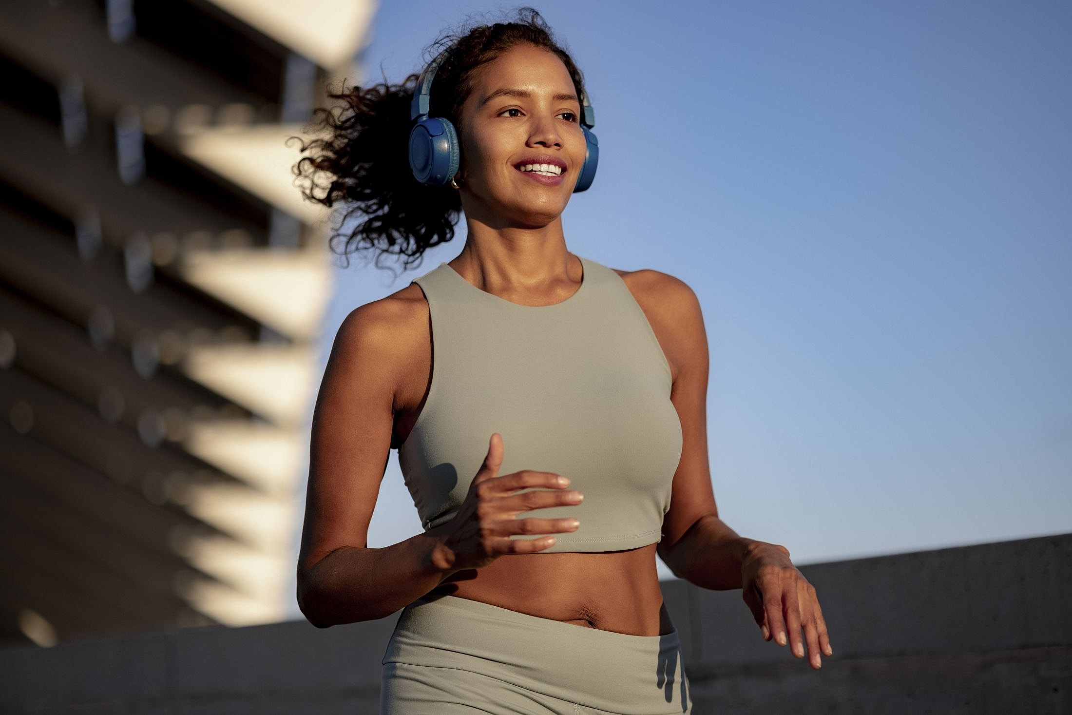 Woman jogging outdoors with headphones on.